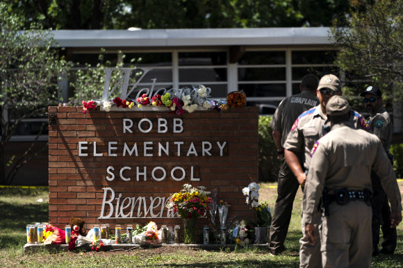 미국 텍사스주 소도시 유밸디의 롭 초등학교에서 총기 난사 사건이 발생한 다음날인 25일(현지시간) 학교 이름이 쓰인 표지석 앞에 희생자들을 추모하는 꽃과 양초들이 놓여 있다. 전날 고등학생 샐버도어 라모스의 무차별 총격으로 이 학교 학생 19명과 교사 2명이 숨졌고 라모스는 사살됐다. 유밸디 AP 뉴시스