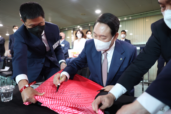 윤석열 대통령이 2일 서울월드컵경기장에서 열린 2002 한일월드컵 20주년 기념 평가전 대한민국-브라질의 경기에서 관중들의 사인요구에 유니폼에 ‘꿈은 이루어진다’라고 적고 있다. 2022.6.2 대통령실사진기자단