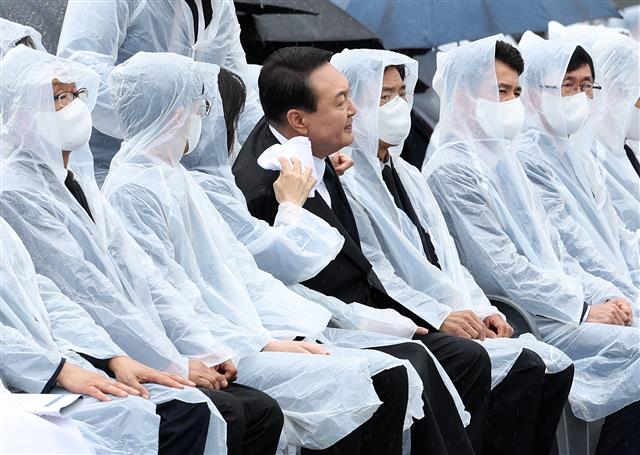 윤석열 대통령 부인 김건희 여사가 6일 서울 동작구 국립서울현충원에서 열린 제67회 현충일 추념식에서 윤 대통령이 양복 자켓에 떨어진 빗물을 수건으로 닦아주고 있다. 2022.6.6 대통령실사진기자단