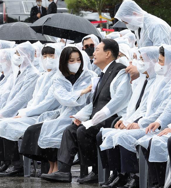 윤석열 대통령 부인 김건희 여사가 6일 서울 동작구 국립서울현충원에서 열린 제67회 현충일 추념식에서 윤 대통령 양복 자켓에 떨어진 빗물을 수건으로 닦아주고 있다.  2022.6.6 대통령실사진기자단