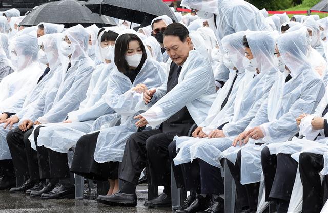 윤석열 대통령 부인 김건희 여사가 6일 서울 동작구 국립서울현충원에서 열린 제67회 현충일 추념식에서 윤 대통령의 우비 착용을 돕고 있다. 2022.6.6 대통령실사진기자단