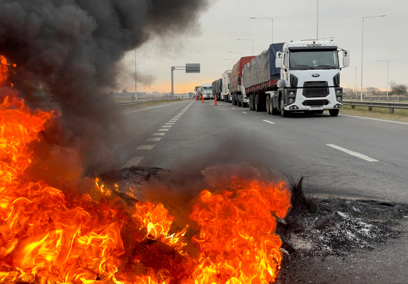 Trucks blocking a highway are pictured near a burning barricade as Argentine truck drivers protest against shortages and rising prices for diesel fuel, just as the country‘s crucial grains harvest requires transport amid surging inflation, in San Nicolas, Argentina June 23, 2022. REUTERS/Miguel Lo Bianco/2022-06-24 08:10:38/ <저작권자 ⓒ 1980-2022 ㈜연합뉴스. 무단 전재 재배포 금지.>