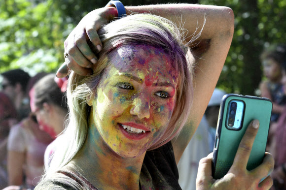 한 여성이 3일(현지시간) 키르기스스탄의 수도 비슈케크에서 열린 힌두교 홀리 축제를 맞아 얼굴에 염료 가루를 뿌린채 셀카를 찍고 있다. AP 연합뉴스