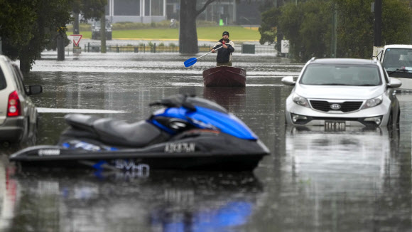 5일(현지시간) 호주 시드니 외곽 윈저에서 한 남성이 물에 잠긴 거리를 노를 저어 지나가고 있다. AP 연합뉴스