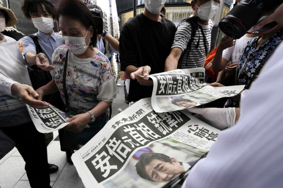아베 신조 전 일본 총리가 8일 나라현에서 선거 유세를 하던 도중 산탄총에 맞아 심폐정지 상태에 빠진 가운데 수도 도쿄도에서 시민들이 이 소식을 전하는 일간지 호외판을 읽고 있다. 도쿄 AP 연합뉴스