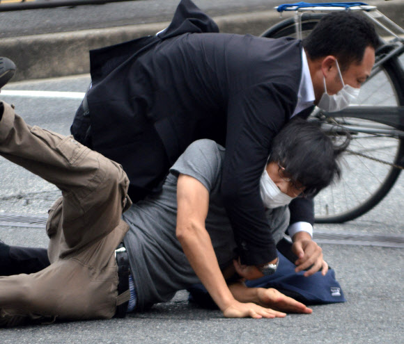 8일 일본 나라현 나라시 야마토사이다이지역 앞에서 참의원 선거 유세활동을 하던 아베 신조 전 일본 총리를 총기로 저격한 용의자 야마가미 데쓰야(아래)가 범행 직후 제압당하고 있다. 로이터 연합뉴스