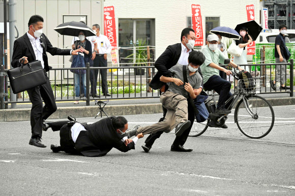 일본 아사히 신문이 8일 아베 신조 전 총리에게 총격을 가해 죽음에 이르게 한 용의자 야마가미 데츠야를 체포하는 과정에 경호원이 넘어지는 와중에도 바지가랑이를 잡고 있는 순간을 포착했다. 아사히 신문 제공 AFP 연합뉴스