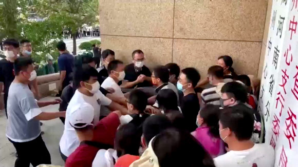 중국 허난성 정저우를 중심으로 여러 마을은행들의 예금 인출 중단에 항의하던 시위대가 10일 정저우 인민은행 지점에 몰려들자 흰옷을 입은 이들이 말려 물리적 충돌이 빚어지고 있다. 정저우 로이터 연합뉴스 