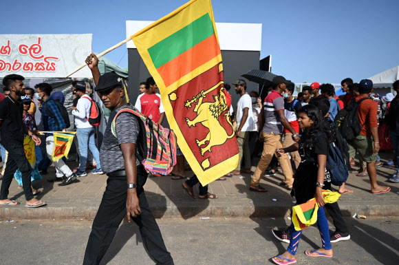 스리랑카 콜롬보의 대통령 집무실 밖에서 국기를 든 시위대가 서성이고 있다. 2022.7.13 AFP 연합뉴스
