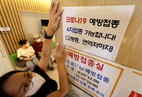 서울에 있는 한 보건소 건강센터 직원이 코로나19 백신 4차 접종 안내문을 붙이고 있다.  연합뉴스