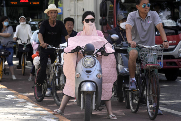 중국의 수도 베이징에서 한 여성이 얼굴에 자외선 차단 마스크를 쓰고 오토바이를 타고 있다. 베이징 AP 연합뉴스