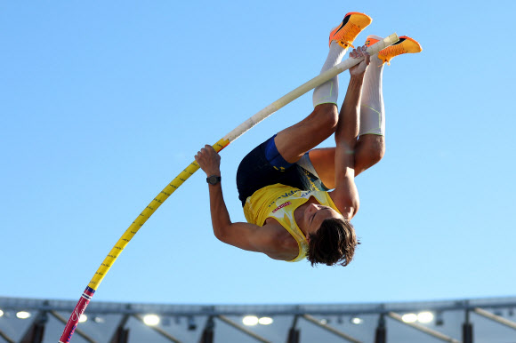 스웨덴의 아먼드 듀플랜티스가 25일(한국시간) 미국 오리건주 유진 헤이워드필드에서 끝난 2022 세계육상선수권대회 남자 장대높이뛰기 결선에서 폴의 탄력으로 하늘 높이 솟구쳐 올라 6m21 높이에 걸린 바를 훌쩍 넘고 있다. 유진(미 오리건주) AFP 연합뉴스