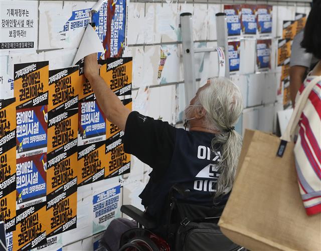 전국장애인철폐연대 박경석 공동대표가 3일 오전 서울 지하철 4호선 삼각지역에서 자신들의 요구가 적힌 스티커가 떼어지자 그 위에 스티커를 덧붙이고 있다. 이날 서울교통공사 관계자에 따르면 해당 스티커는 지하철을 찾은 시민들이 전장연 집회에 대한 반발심으로 떼었을 가능성이 크다. 지하철 직원 혹은 청소부는 스티커에 일절 손을 대지 않는것이 현재 교통공사 방침이기 때문이다. 2022.8.3 뉴스1