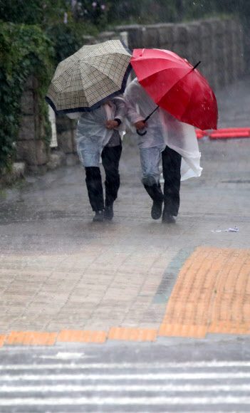 서울 등 중부를 중심으로 폭우가 쏟아지는 8일 오후 서울 여의도 국회 정문 앞에서 시민들이 우산을 쓰고 지나가고 있다. 2022.08.08. 뉴시스