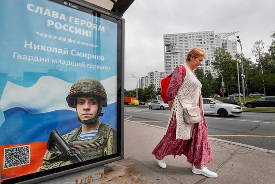 러시아 모스크바의 한 버스정류장에 러시아 병사 사진과 ‘러시아의 영웅들에게 영광을’이란 문구가 적혀있는 포스터가 걸려 있다. EPA 연합뉴스