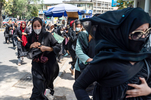 아프가니스탄 카불에서 지난 13일(현지시간) 탈레반 무장대원들이 여성 인권 탄압에 항의하며 거리로 나선 시위대를 향해 발포하자 여성들이 놀라 대피하고 있다. 카불 AFP 연합뉴스