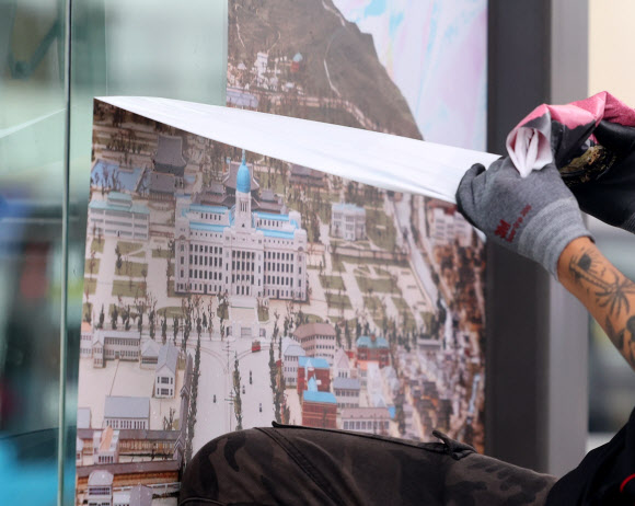 30일 오후 최근 재개장한 서울 광화문광장 버스정류장에서 서울시 관계자들이 조선총독부 등이 포함된 대형 포스터를 제거하고 있다. 2022.8.30  연합뉴스