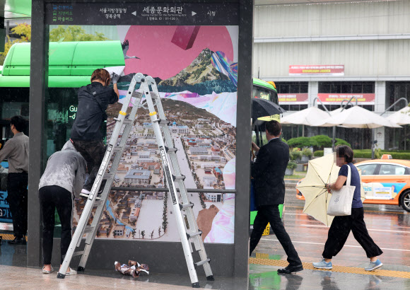 30일 오후 최근 재개장한 서울 광화문광장 버스정류장에서 서울시 관계자들이 조선총독부 등이 포함된 대형 포스터를 제거하고 있다. 2022.8.30  연합뉴스