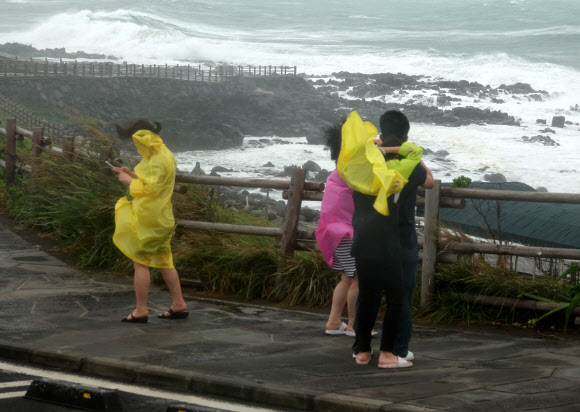 5일 오전 제주 송악산을 찾은 관광객들이 높은 파도가 일고 있는 해안가를 배경으로 사진을 찍고 있다. 이날 제주에는 제11호 태풍 힌남노의 영향으로 강풍을 동반한 많은 비가 내리고 있다. 2022.09.05. 뉴시스