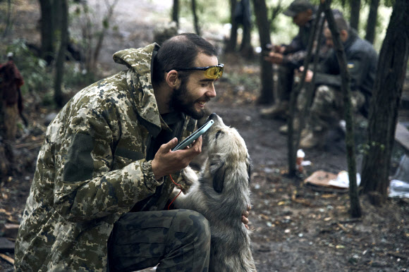 우크라이나가 최근 수복한 하르키우 지역에서 한 우크라이나군 병사가 휴식을 취하면서 개와 놀고 있다. 볼로디미르 젤렌스키 우크라이나 대통령은 12일(현지시간) 우크라이나군이 이달 들어 동부와 남부에서 6000㎢ 이상의 영토를 탈환했다고 밝혔다. 2022.9.12 AP 연합뉴스
