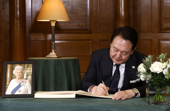 윤석열 대통령이 19일 영국 런던 웨스트민스터사원에서 엄수된 엘리자베스 2세 여왕 장례식에 참석한 뒤 조문록을 작성하고 있다. 연합뉴스
