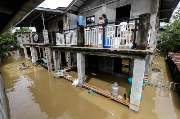 필리핀 마닐라 북쪽 불라칸주 산미구엘 마을에서 태풍 노루로 인한 홍수가 발생한 가운데 주민들이 집 위층에서 밖을 내다보고 있다. 태풍 노루는 9월 25일 필리핀 북부 루손 지역을 가로질러 폭우와 강풍으로 인해 수천 명의 사람들이 대피했다. 태풍 노루는 9월 26일 저녁까지 필리핀 지역을 떠날 것으로 예상된다. 2022. 9. 26 EPA 연합뉴스