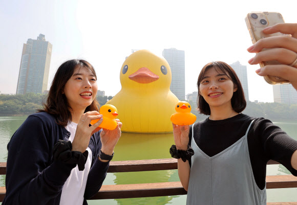 29일 오전 서울 송파구 석촌호수 동호에 설치된 러버덕 앞에서 전시 관계자들이 기념촬영을 하고 있다. 2014년 이후 8년 만에 다시 돌아온 러버덕은 플로렌타인 호프만 작가가 제작한 작품으로 10월 31일까지 전시된다. 2022.9.29  연합뉴스