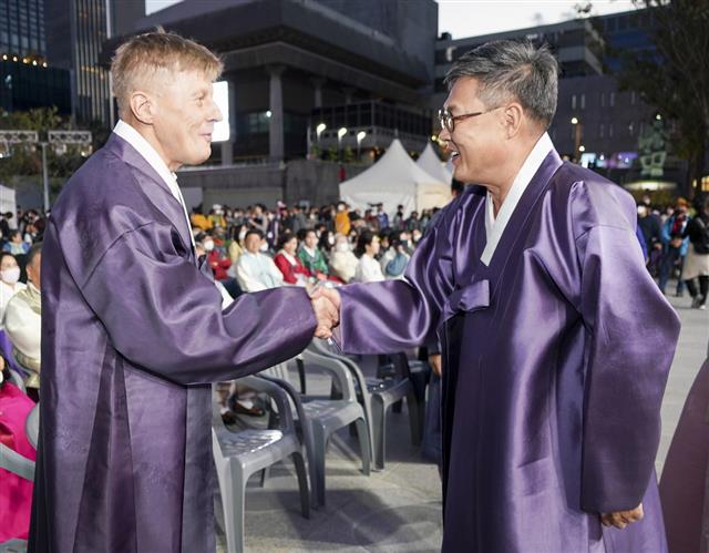 서울 종로구가 개최한 ‘2022 종로한복축제’가 열린 지난 8일 광화문광장에서 한복을 입은 정문헌(오른쪽) 종로구청장이 프레드리크 엑펠트 주한 유럽연합 부대사와 악수하고 있다.<br>종로구 제공