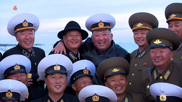 북한 김정은 국무위원장이 노동당 창건일인 지난 10일 함경남도 함주군 연포지구의 대규모 남새(채소)생산기지인 연포온실농장 준공식에 참석해 준공 테이프를 끊었다고 조선중앙TV가 11일 보도했다. 김 위원장이 김명식 해군사령관과 모자를 바꿔 쓰고 기념촬영 하며 활짝웃고 있다. 2022.10.11  조선중앙TV 화면