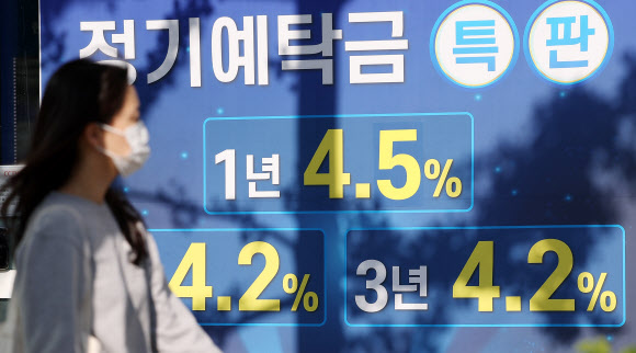 한 시민이 13일 오후 서울 시내의 한 은행에 붙은 정기예탁금 안내 현수막 앞을 지나가고 있다. 연합뉴스