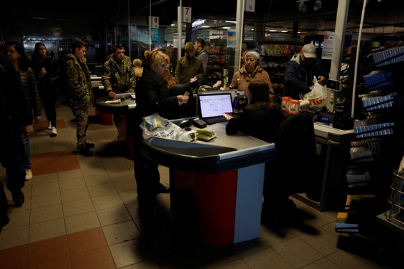 17일(현지시간) 우크라이나 하르키우에 러시아 공격으로 정전이 발생한 가운데, 주민들이 어두컴컴한 슈퍼마켓에서 장을 보고 있다. 2022.10.17  로이터 연합뉴스