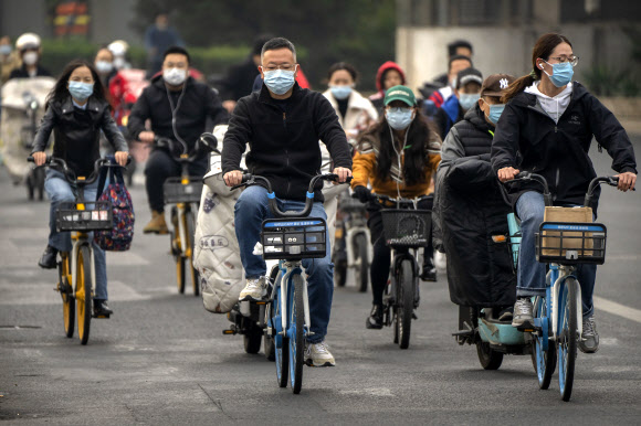 베이징 시민들이 코로나19 방역 마스크를 쓴 채 자전거를 타고 출근하고 있다. 2022.10.20 AP 연합뉴스