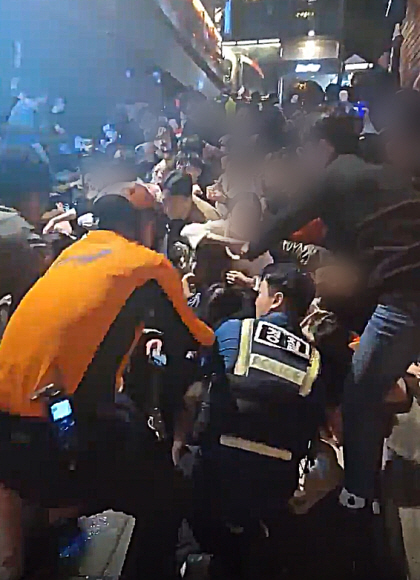 경찰과 시민들이 29일 밤 이태원동 해밀톤호텔 옆에서 압사 사고 당시 밑에 깔린 희생자들을 구하기 위해 애쓰고 있다.<br>SNS 캡처