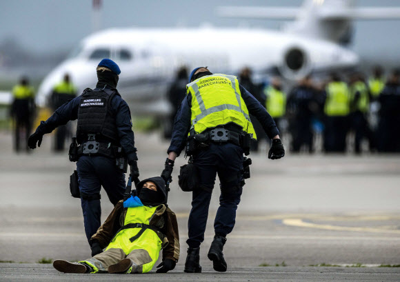 네덜란드 군사경찰들이 5일(현지시간) 암스테르담 스히폴 공항 활주로에 난입해 개인 제트기 이륙을 방해하던 기후활동가를 질질 끌어 연행하고 있다. 암스테르담 EPA 연합뉴스