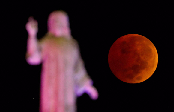 2022년 11월 8일 엘살바도르 산살바도르에서 조각상 너머로 월식이 일어나는 달의 모습이 보이고 있다. REUTERS/Jose Cabezas