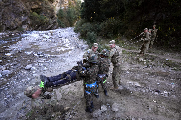 인도군 병사들과 함께 11공수사단 2여단 소속 미군 병사들이 30일(현지시간)  인도 우타라칸드주 타포반에서 인도-미국 합동훈련 중 인도주의 지원과 재난구호 작전으로 부상당한 마을 주민을 끌어내리는 모의훈련을 하고 있다. 인도와 미국의 군인들이 중국과의 분쟁 중인 인도 국경과 가까운 춥고 산악 지형에서 고공 훈련에 참가하고 있다. 2주 전부터 시작된 훈련은 북부 우타라칸드 주의 언덕 아울리 주변에서 열린다. AP 연합뉴스