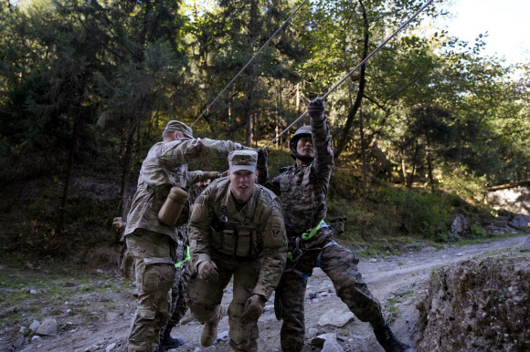 인도군 병사들과 함께 11공수사단 2여단 소속 미군 병사들이 30일(현지시간)  인도 우타라칸드주 타포반에서 인도-미국 합동훈련 중 인도주의 지원과 재난구호 작전으로 부상당한 마을 주민을 끌어내리는 모의훈련을 하고 있다. 인도와 미국의 군인들이 중국과의 분쟁 중인 인도 국경과 가까운 춥고 산악 지형에서 고공 훈련에 참가하고 있다. 2주 전부터 시작된 훈련은 북부 우타라칸드 주의 언덕 아울리 주변에서 열린다. AP 연합뉴스