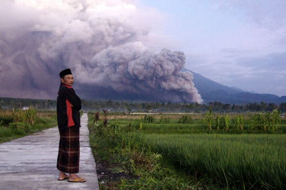 A man looks on as Mount Semeru releases volcanic materials during an eruption on Sunday, Dec. 4, 2022 in Lumajang, East java, Indonesia. Indonesia’s highest volcano on the country’s most densely populated island of Java erupted Sunday. (AP Photo)/2022-12-04 14:28:47/ <연합뉴스>