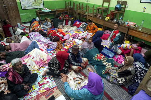 People rest at a school turned into temporary shelter for those evacuated from their homes following the eruption of Mount Semeru, in Lumajang, East Java, Indonesia, Sunday, Dec. 4, 2022. Indonesia‘s highest volcano on its most densely populated island released searing gas clouds and rivers of lava Sunday in its latest eruption. (AP Photo/Dicky Bisinglasi)/2022-12-04 22:54:55/ <연합뉴스>