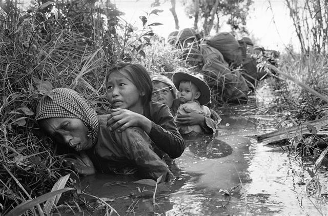 1966년 베트남 바오짜이 마을에서 여성과 어린 아이들이 진흙탕 속에서 웅크린 채 공습을 피하는 모습. AP 연합뉴스