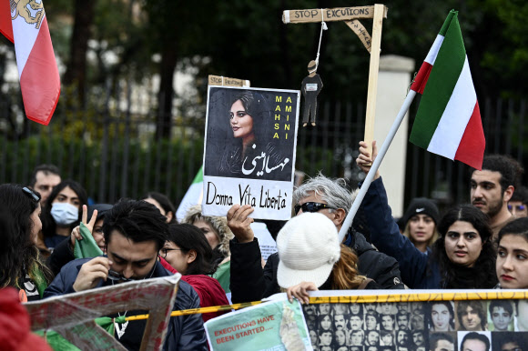 한 시위 참가자가 10일(현지시간) 이탈리아 로마에서 열린 시위에 참가해 히잡 착용 문제로 경찰에 구금됐다 숨진 마샤 아미니가 그려진 플래카드를 들고 있다. 로마 EPA 연합뉴스