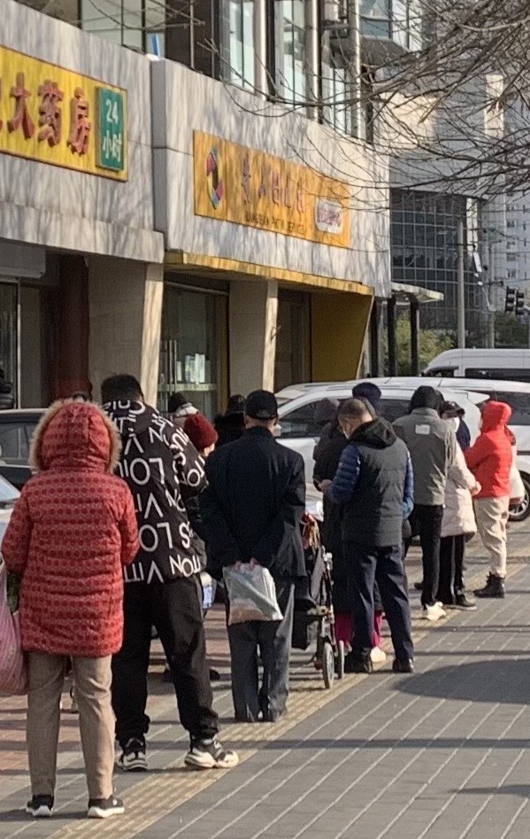 지난 10일 중국 베이징동계올림픽 주경기장인 냐오차오(鳥巢·새둥지) 인근 아파트 단지에서 주민들이 의약품을 사재기하고자 약국 입구에서 장사진을 이루고 있다.