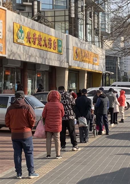 지난 10일 중국 베이징동계올림픽 주경기장인 냐오차오(鳥巢) 인근 아파트 단지에서 주민들이 의약품을 사재기하고자 약국 입구에서 장사진을 이루고 있다. 베이징 류지영 특파원