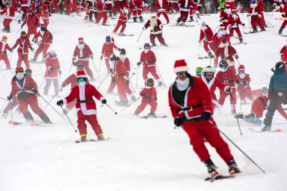 11일(현지시간) 미국 메인주 뉴리의 선데이 리버 스키 리조트에서 산타 복장을 한 사람들이 스키를 타고 슬로프를 내려가고 있다. AFP 연합뉴스