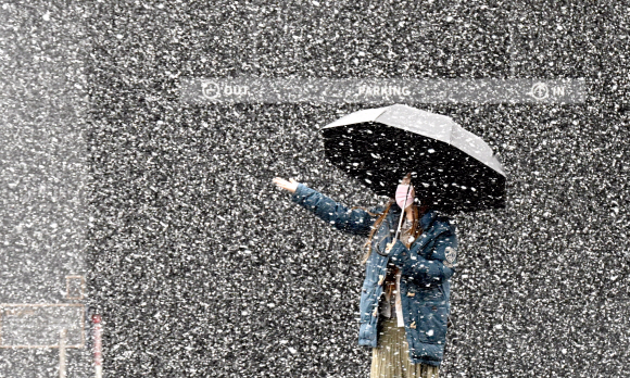 눈이 내린 13일 서울 서초구의 한 거리에서 시민이 우산을 쓴채 눈을 맞고 있다. 2022.12.13  박지환 기자