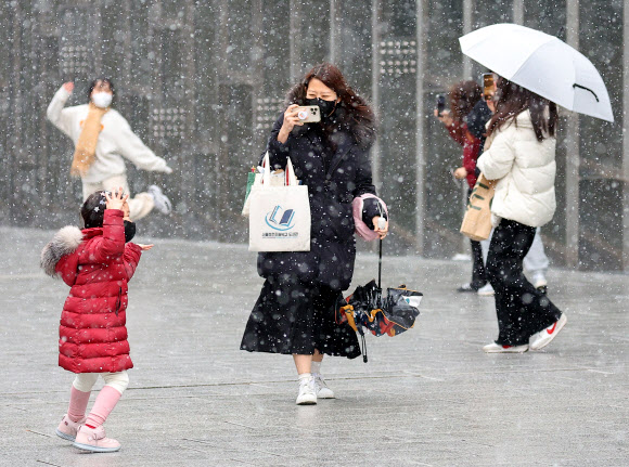 본격적인 겨울을 알리는 눈이 내린 13일 오후 서울 서대문구 이화여자대학교를 찾은 모녀가 활짝 웃으며 영상을 남기고 있다. 2022.12.13  연합뉴스