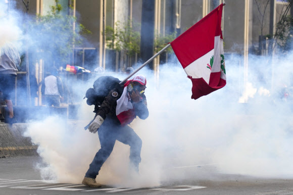 탄핵된 페루 전 대통령 페드로 카스티요의 지지자가 12일(현지시간) 최루 가스통을 경찰에게 던지고 있다. 리마 AP