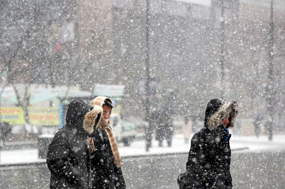 눈이 내리고 있는 15일 오후 서울 종로구 광화문에서 시민들이 모자를 쓰고 이동하고 있다. 2022.12.15. 뉴시스
