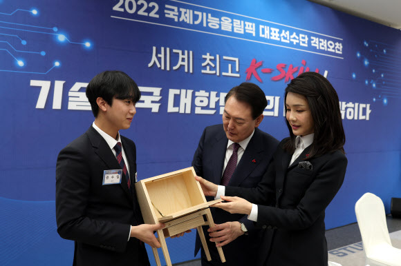 윤석열 대통령과 부인 김건희 여사가 16일 경기 성남 분당구 한국잡월드에서 열린 국제기능올림픽 선수단 격려 오찬에서 ‘가구 종목’ 금메달을 수상한 권수일 선수에게 출품 가구 모형을 선물받고 있다. 2022.12.16. 대통령실 제공