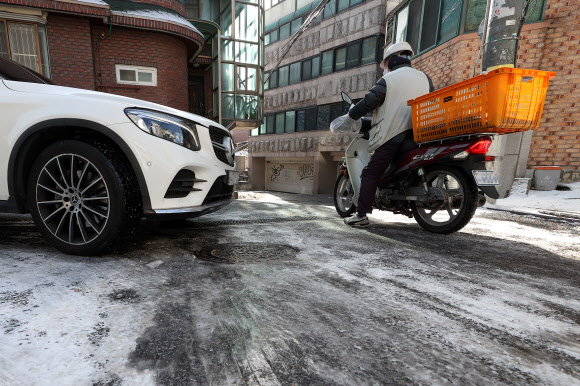16일 오후 서울 용산구청 인근 주택가에서 오토바이 운전자가 눈이 녹지 않은 이면도로에서 이동하고 있다. 2022.12.16 연합뉴스